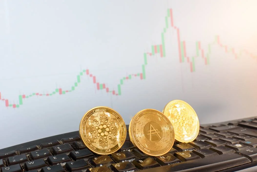  Mata uang digital Cardano, ADA, dalam koin emas, pada keyboard komputer broker 