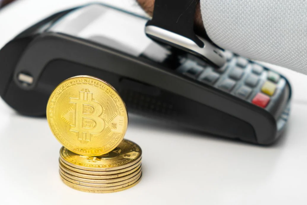  Golden bitcoin coins next to payment terminal on the table 