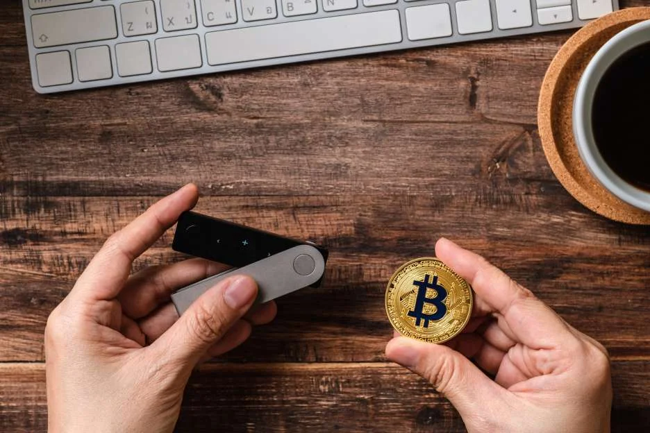  Hand holding hardware wallet and a bitcoin 