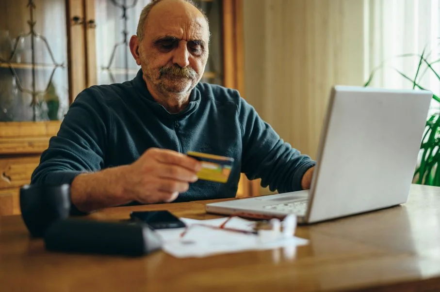  Man using a laptop and holding a credit card 