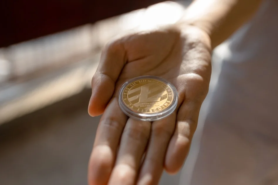  Young man holding LTC Litecoin on palm of hand 