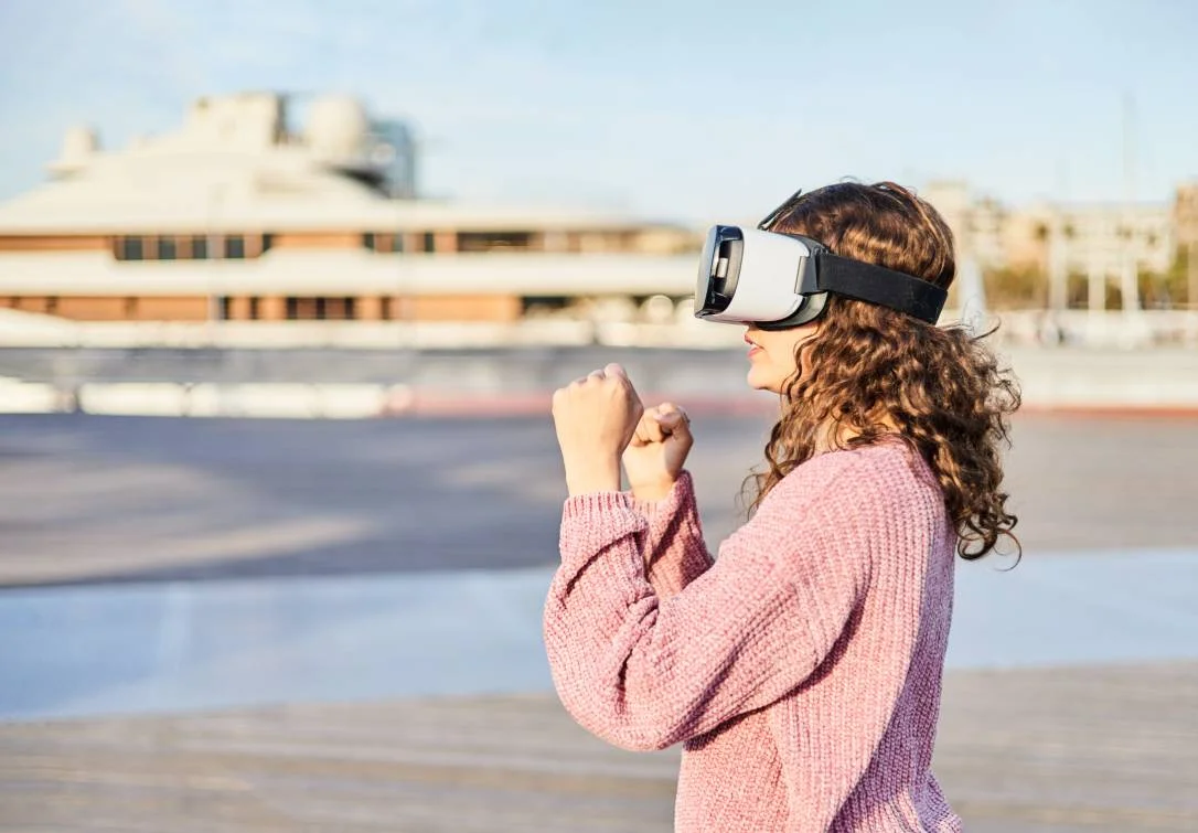  Young woman fights in a metaverse video game with VR goggles. 